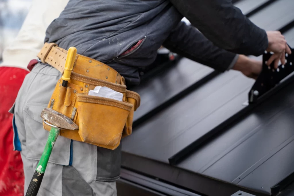 Construction worker preventing lost shingles by securing them with his belt